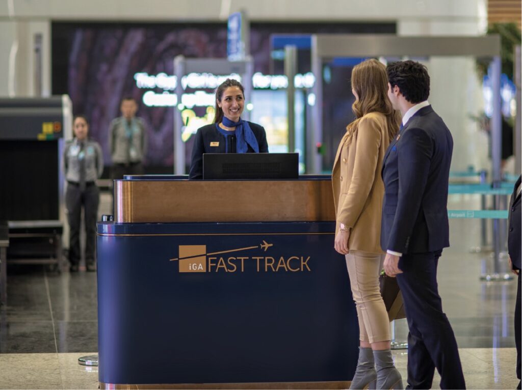 Travelers being assisted at a "Fast Track" airport counter by staff
