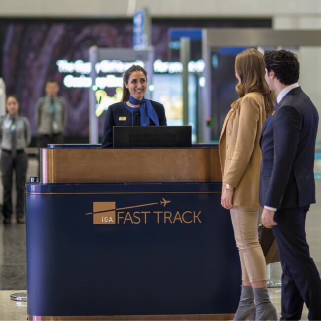 Travelers being assisted at a "Fast Track" airport counter by staff