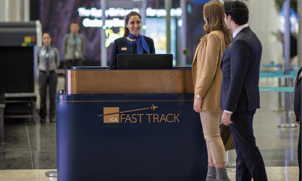 Travelers being assisted at a "Fast Track" airport counter by staff