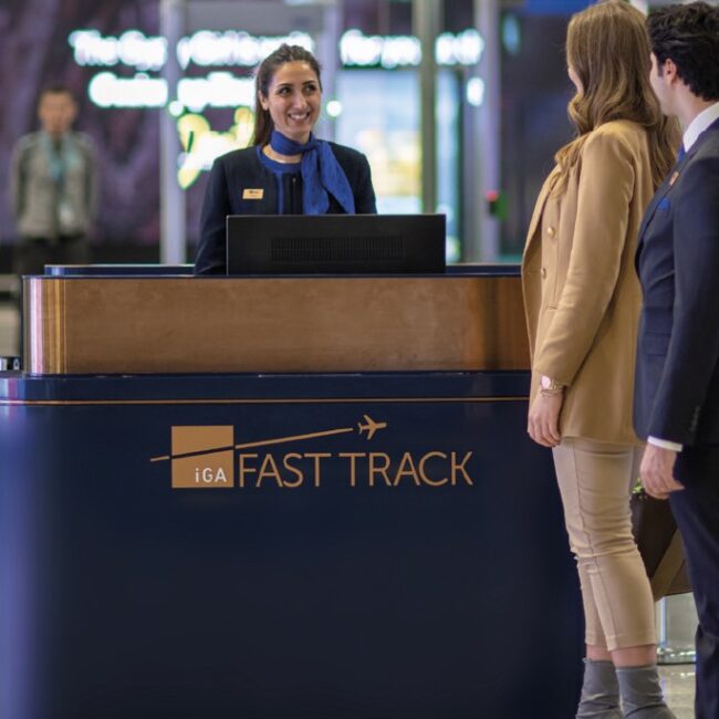 Travelers being assisted at a "Fast Track" airport counter by staff