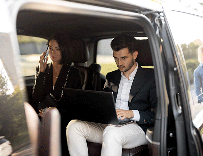 Business team working on a laptop inside a luxury VIP minibus, demonstrating a productive mobile office solution by Limousine Plus in Istanbul.