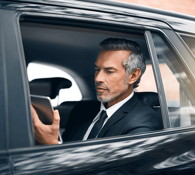 A senior executive working on a tablet in the backseat of a Limousine Plus vehicle, utilizing travel time for business during a transfer in Istanbul.