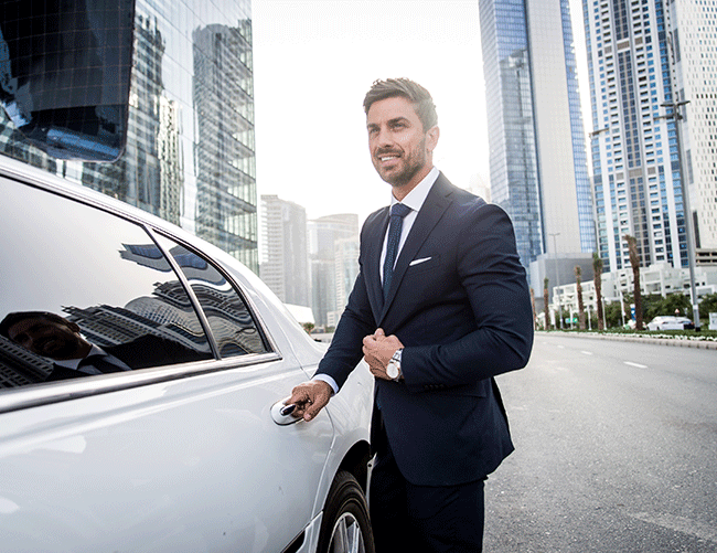 A successful businessman arriving in Istanbul's business district, opening the door of his white luxury car provided by Limousine Plus.